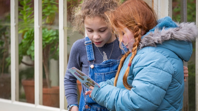 Two children in the Botanic Garden at Lacock look at a flower spotter sheet